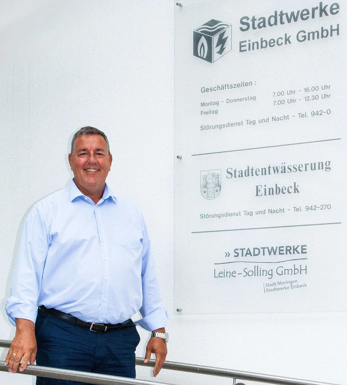 Geschäftsführer der Stadtwerke Einbeck steht lächelnd negen dem Eingangschild der Stadtwerke Einbeck, der Stadtentwässerung und der Stadtwerke Leine-Solling. 