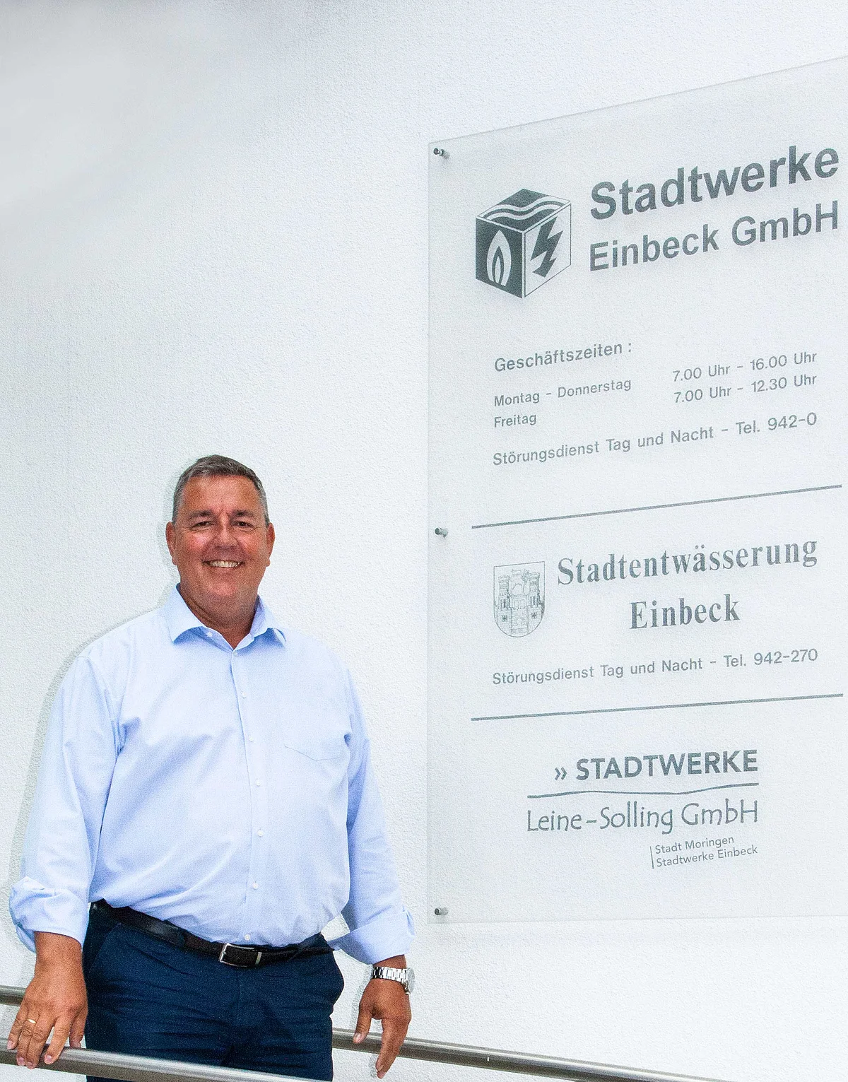 Geschäftsführer der Stadtwerke Einbeck steht lächelnd negen dem Eingangschild der Stadtwerke Einbeck, der Stadtentwässerung und der Stadtwerke Leine-Solling. 